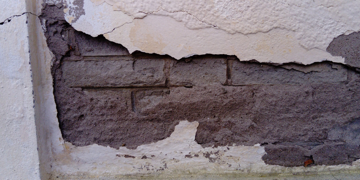 Abgeplatzter Putz mit feuchtem Mauerwerk als typisches Schadensbild ohne Horizontalsperre