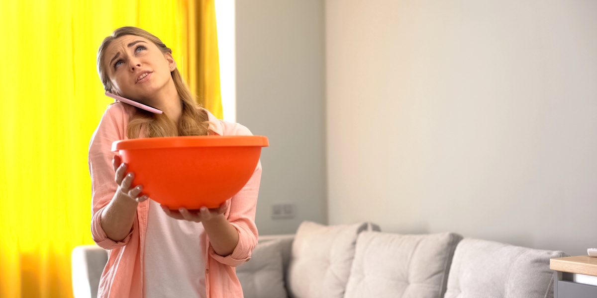 Wasser tropft von der Decke in Schüssel bei akutem Wasserschaden