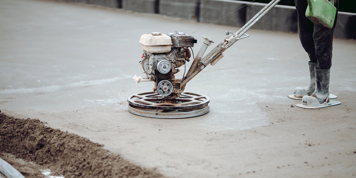 Glättmaschine verdichtet frischen Betonboden zur Herstellung einer ebenen Oberfläche bei Beton auf Beton