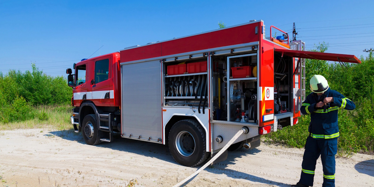 Feuerwehrfahrzeug mit Pumpenausrüstung und Feuerwehrmann im Einsatz zum Keller auspumpen nach Wasserschaden