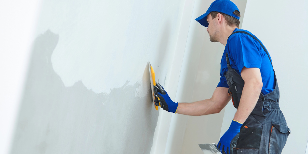 Handwerker glättet Innenwand bei der Sanierung feuchter Wände im Altbau