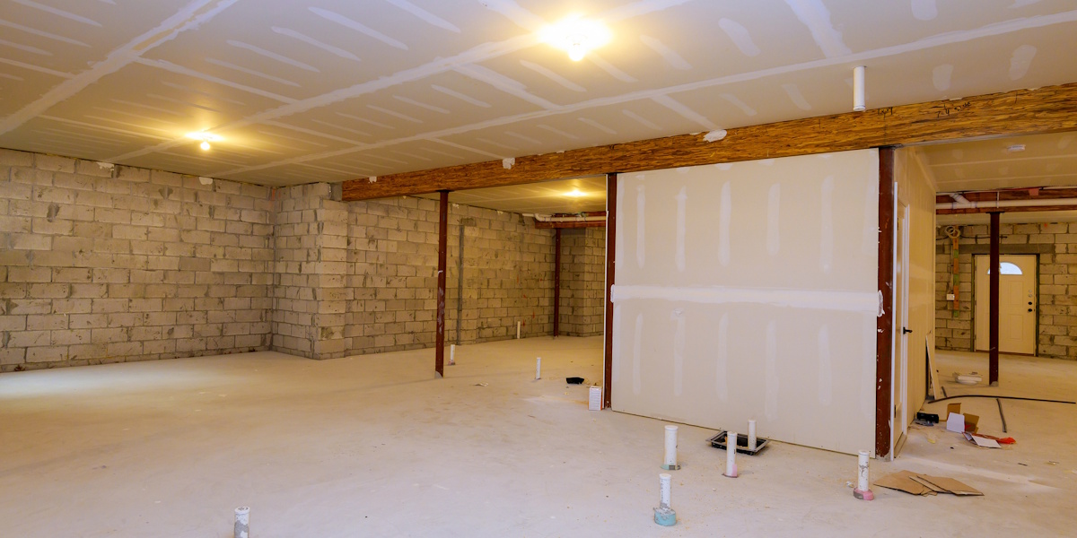 Rohkeller mit Betonboden, Mauerwerk und sichtbaren Installationen während der Bau- oder Sanierungsphase zur Kellerabdichtung