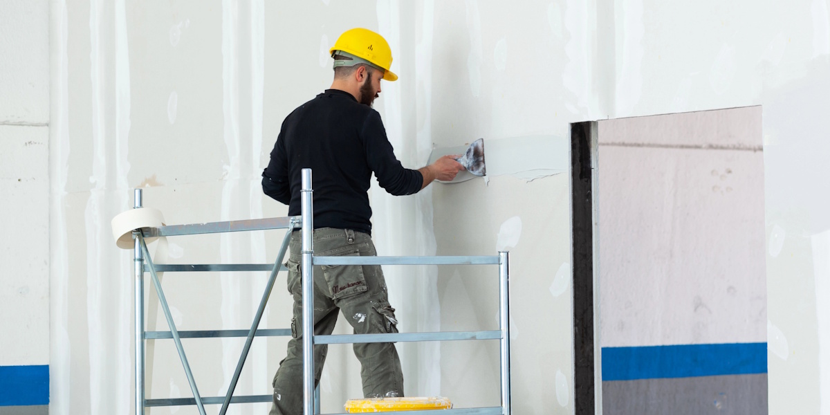Handwerker verspachtelt Gipskartonwand bei Trockenbauarbeiten
